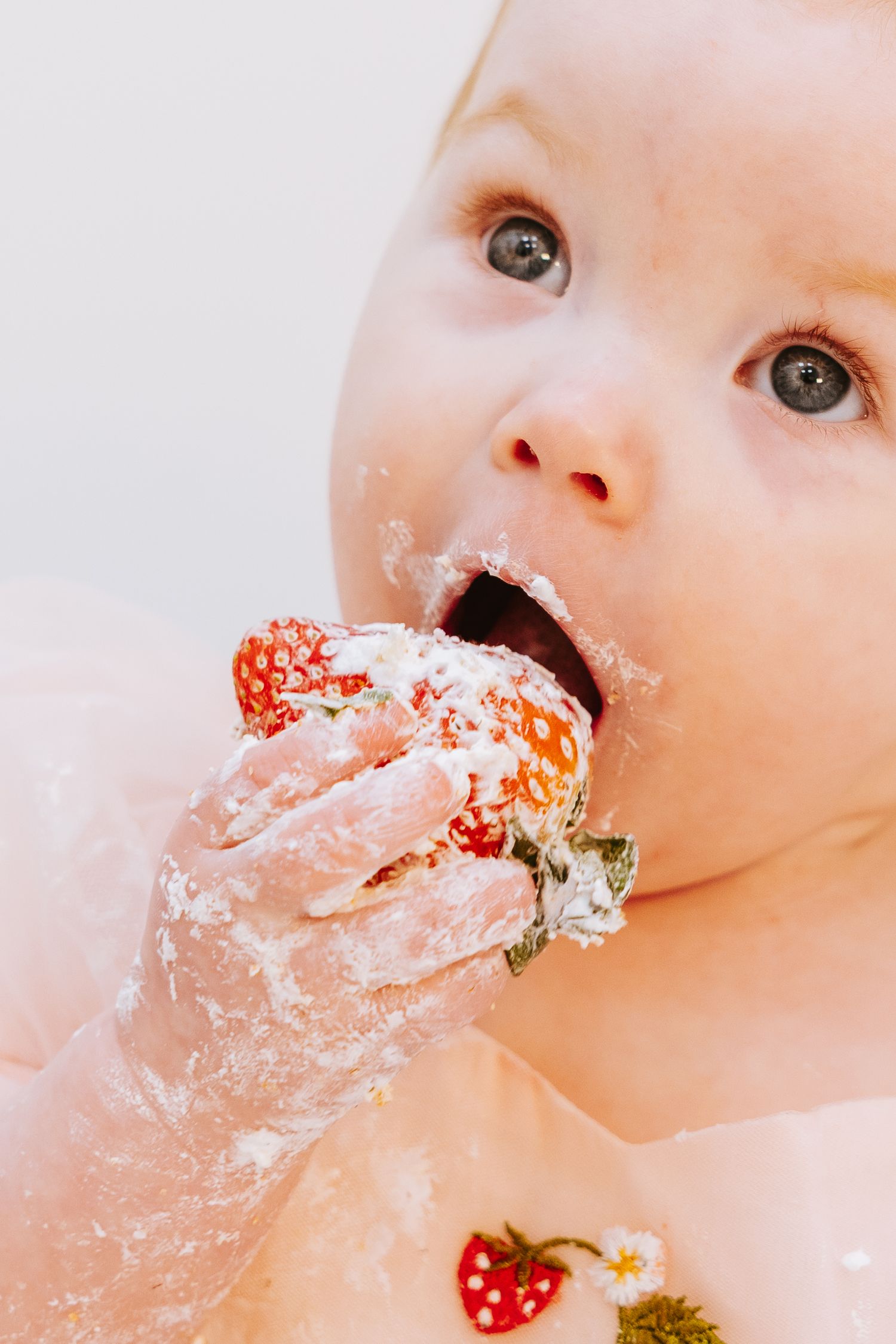 Close-up shot of cake smashing moment with frosting and strawberries.