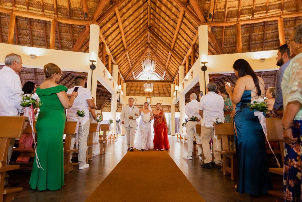 Wedding ceremony in a rustic wooden chapel with vaulted ceilings and guests in white attire.