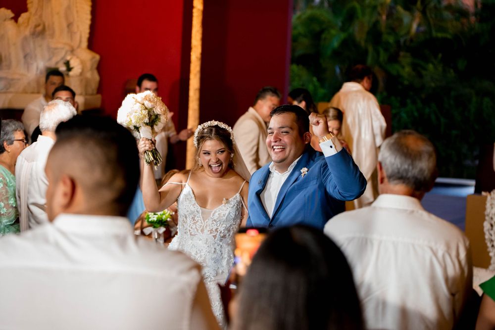 Wedding party entrance into a tropical venue filled with guests and festive decorations.
