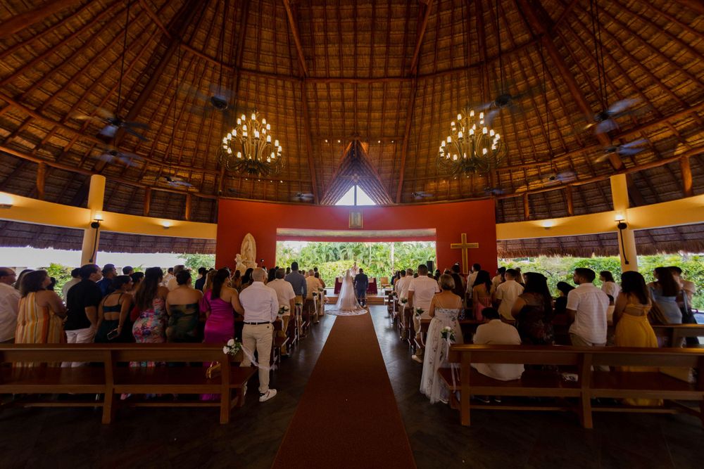 Interior of a grand circular wedding venue with chandeliers and red carpet aisle.