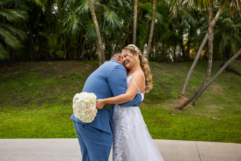 A romantic embrace between a couple surrounded by tropical palm trees and greenery.