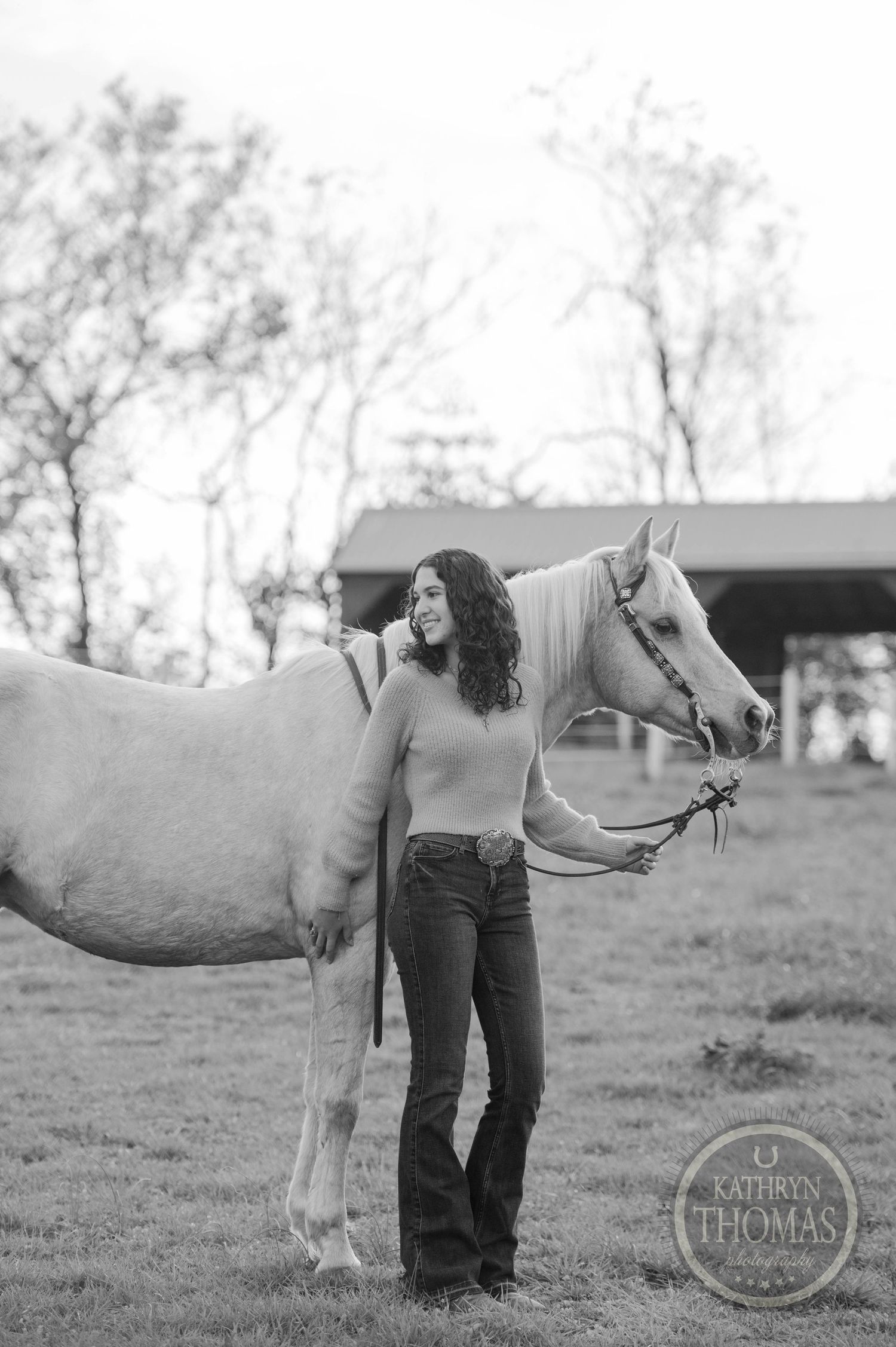 Black and white portrait of person with horse in countryside setting.