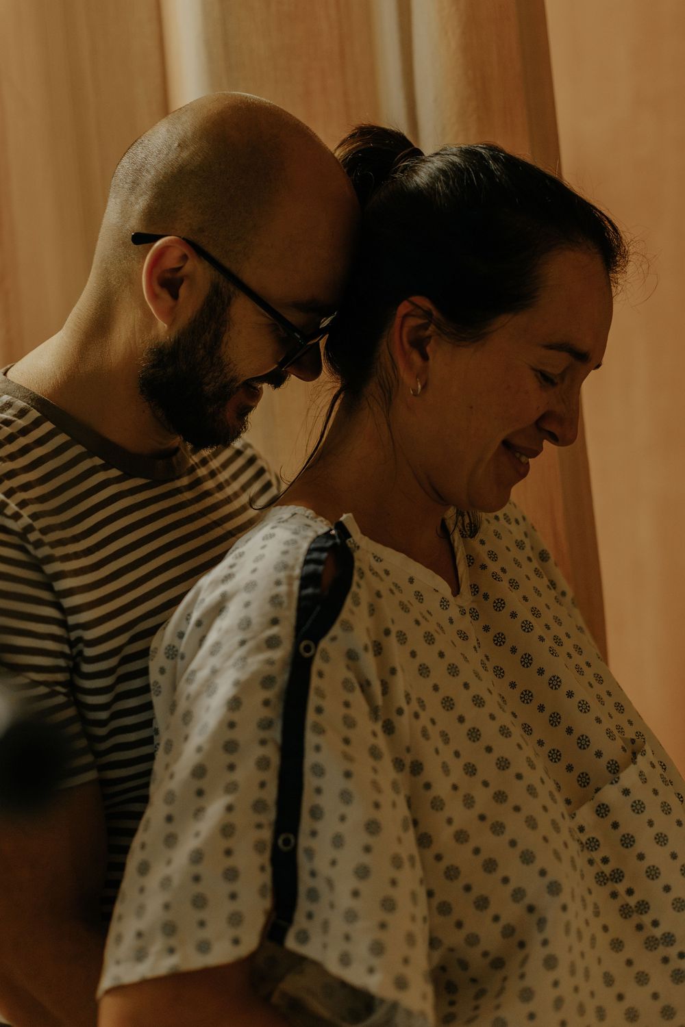 Dad on the back of the mom, massaging her to relieve the pain of the contractions and they are both smiling