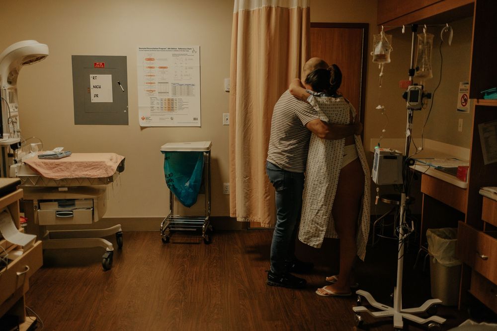 mom and dad hugging each other in the hospital room during her active labour, going through contractions and pain