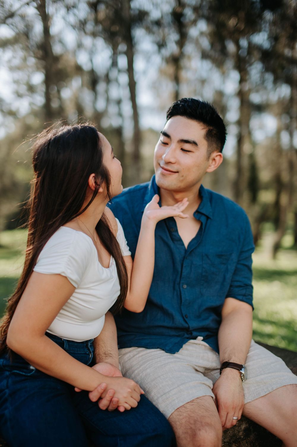 An intimate moment between a couple sitting together outdoors in natural lighting.