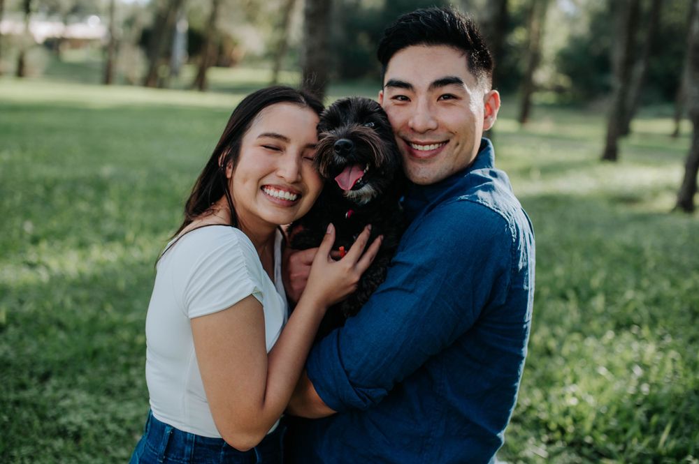 Couple shares happy moment with their black dog during outdoor photo session.