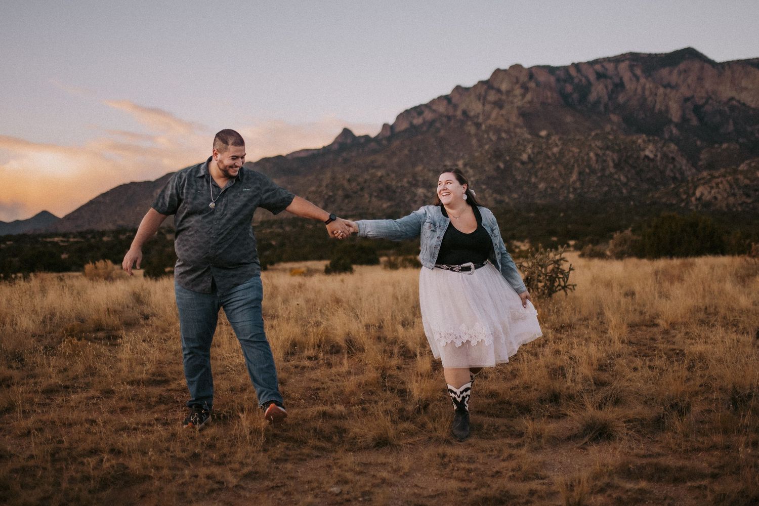 Couple dancing in the foothills at sunset with the sandia mountains in the background. Albuquerque photo session style guide. What to wear.