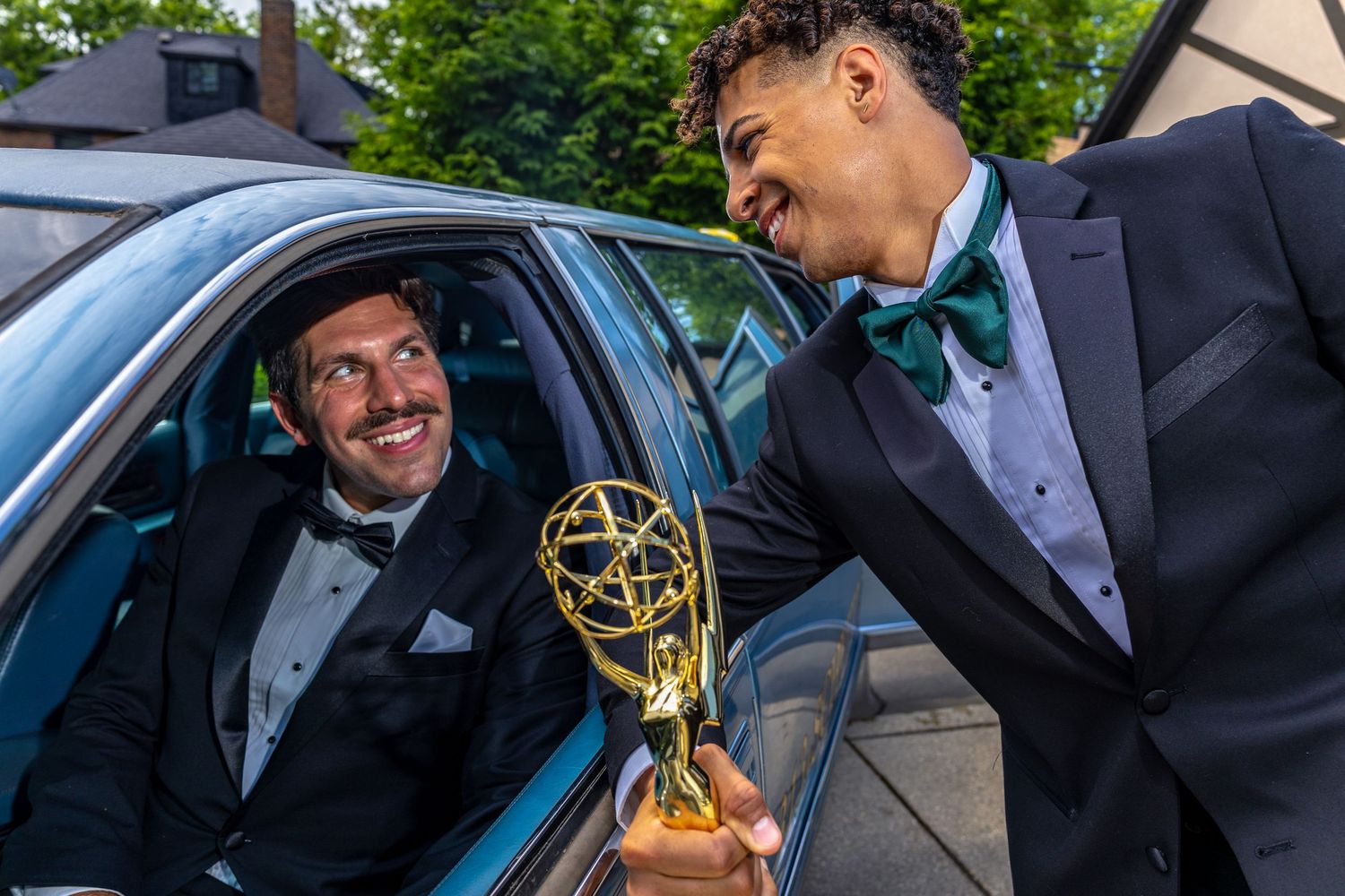 Men holding an Emmy award wearing tuxedos posing in an editorial photograph