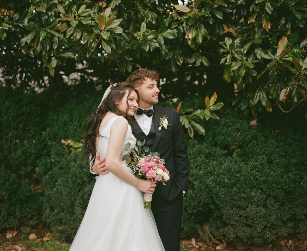 Medium format film photo of groom holding his bride gazing in the distance