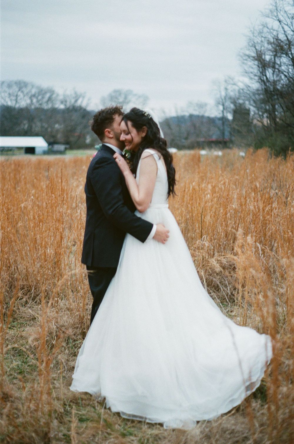Bride and groom hug in a golden field of tall grass