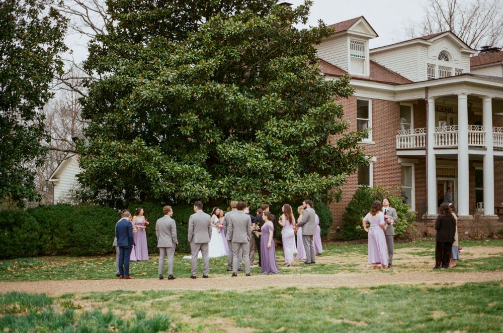 Bridal party stand and mingle in front of historic home venue
