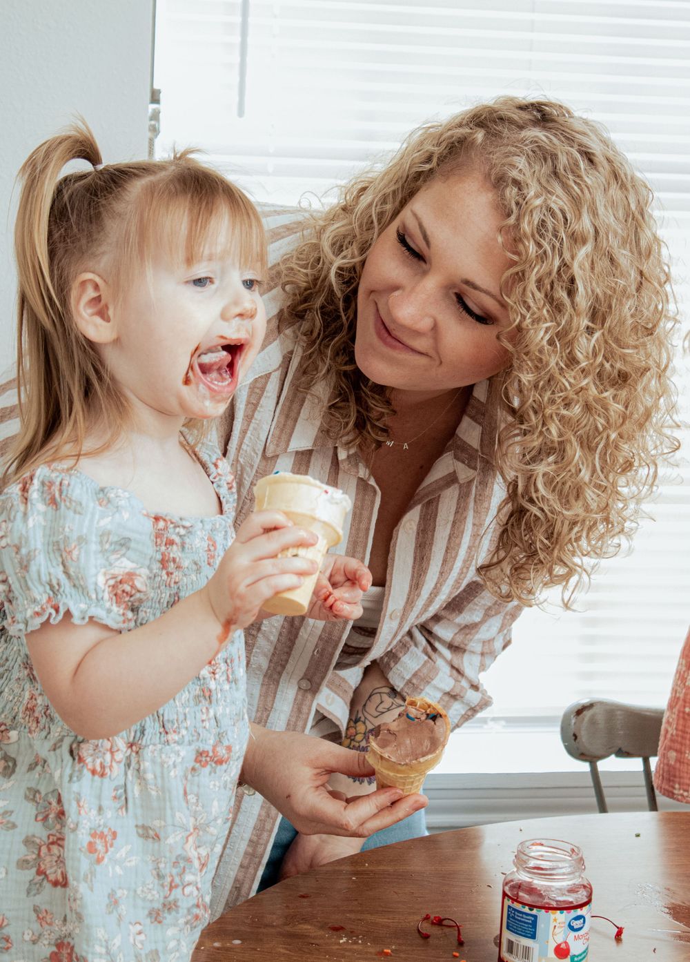 Parent and child sharing ice cream treats while sitting at table together.