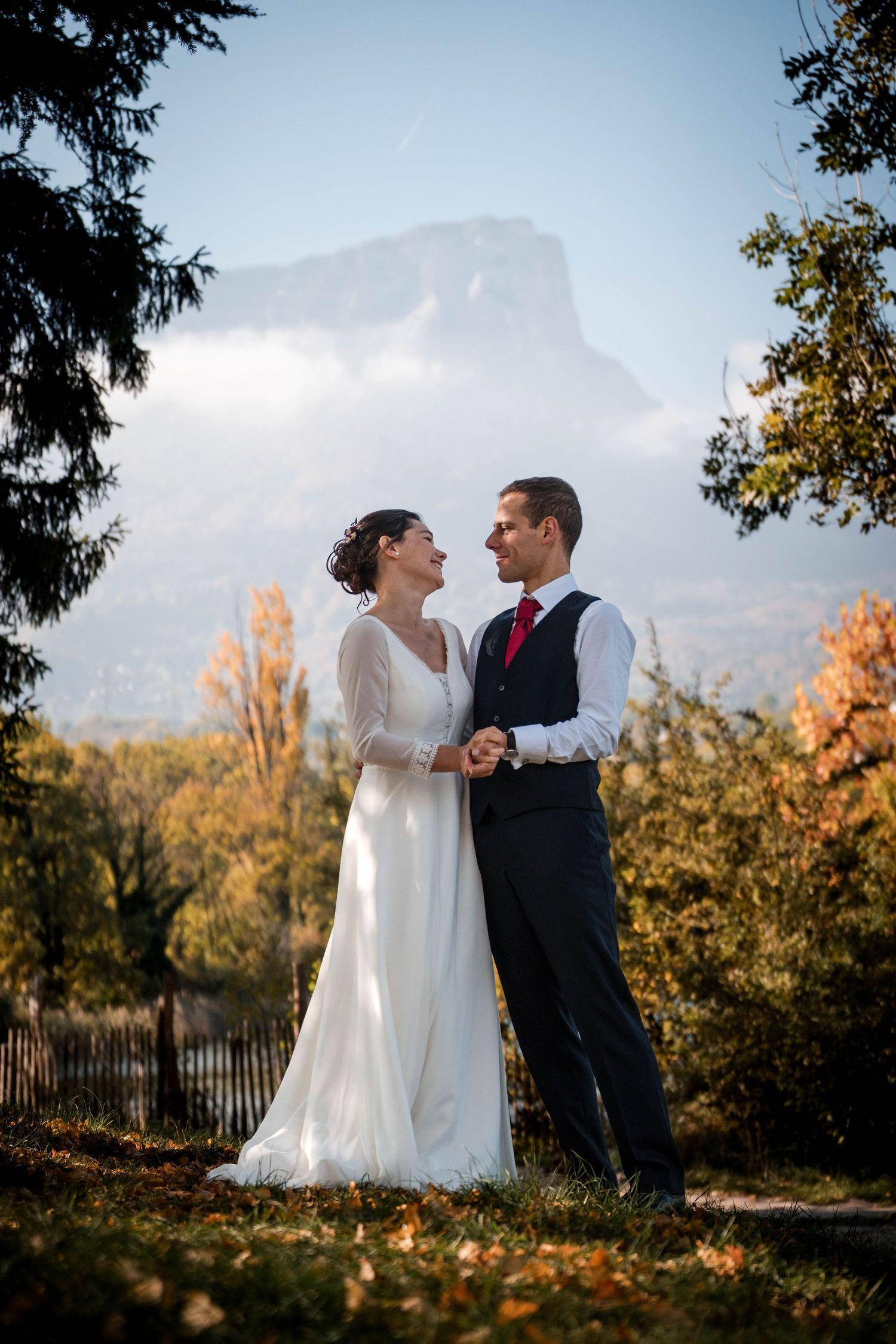 Un couple joyeux partage un moment intime sous un délicat voile blanc lors de leur cérémonie de mariage en plein air.