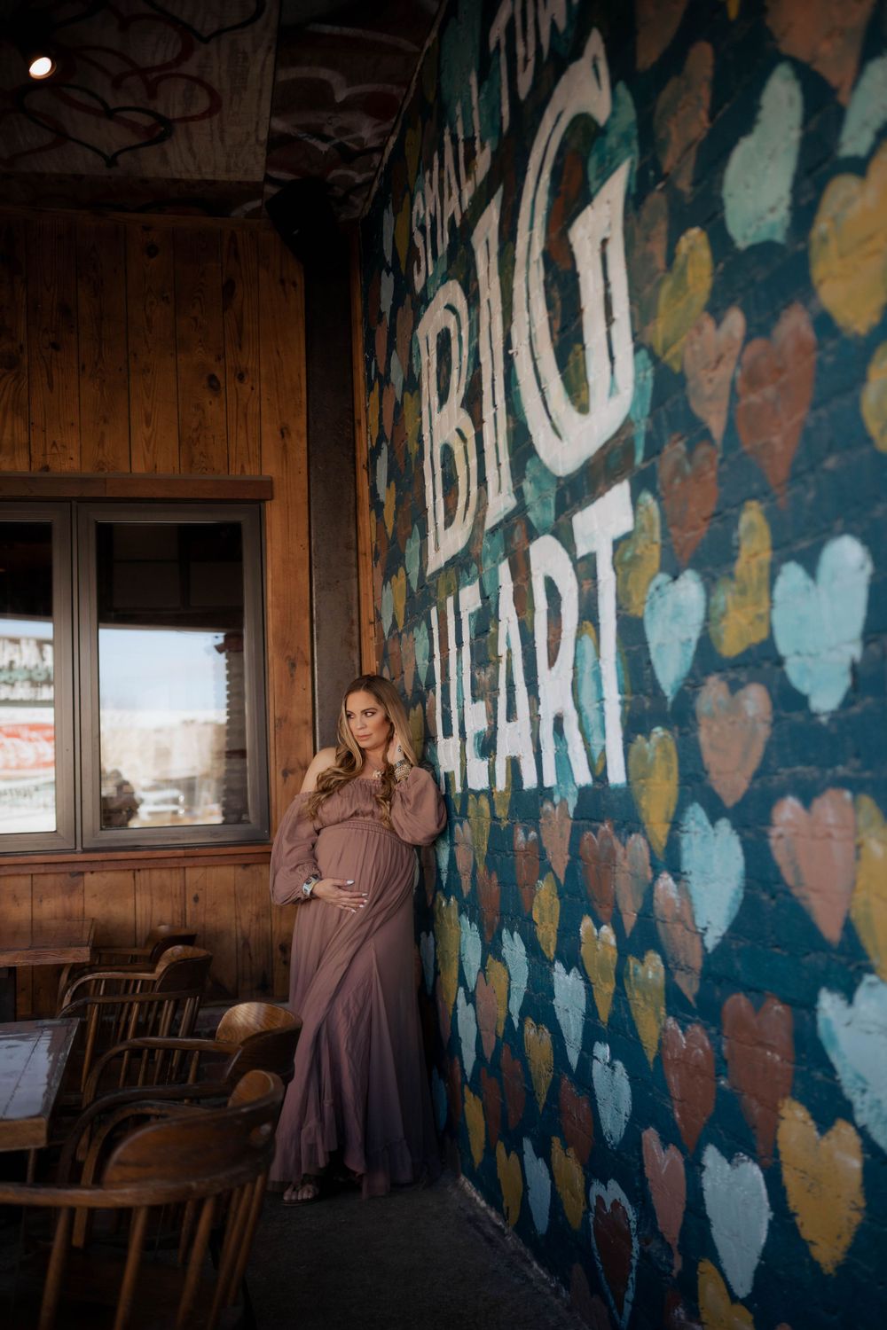 A moody interior scene shows colorful heart-shaped wall art and rustic wood paneling at a venue called Big Heart.