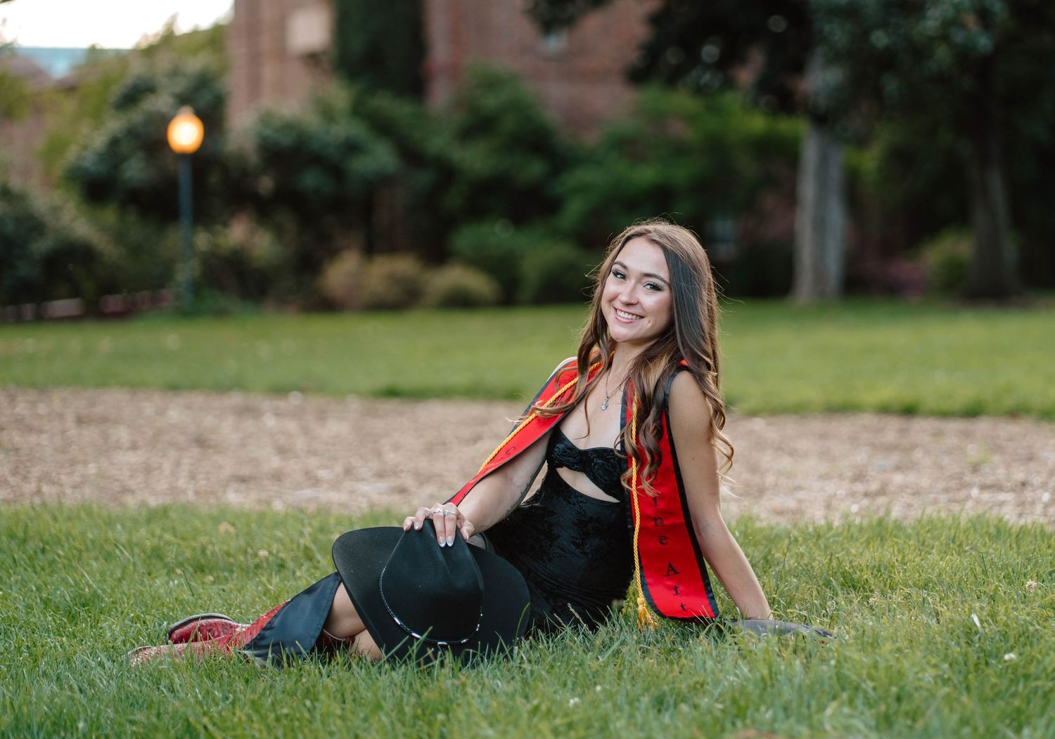Young woman in a red boho skirt posing in a golden sunlit meadow.
