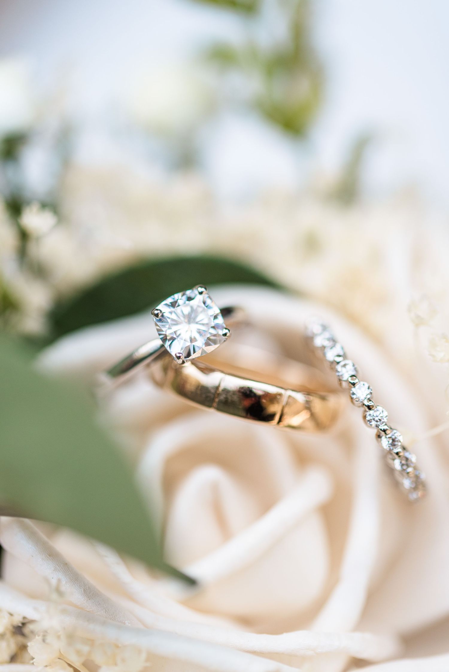 Elegant diamond engagement ring and wedding band nestled on a white rose petal.