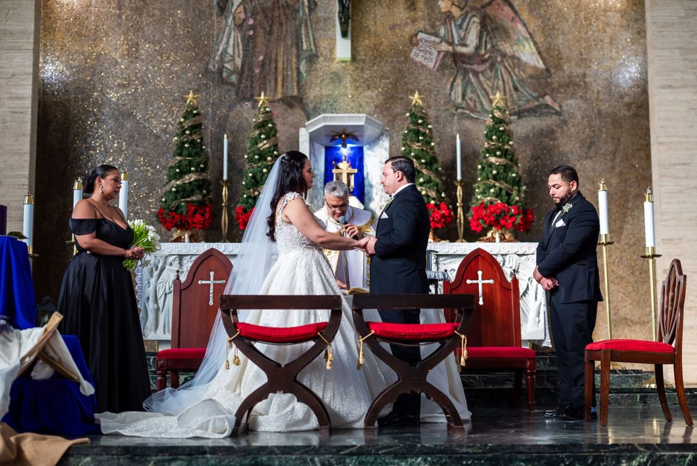 Wedding ceremony at an ornate church altar with Christmas decorations and religious artwork.