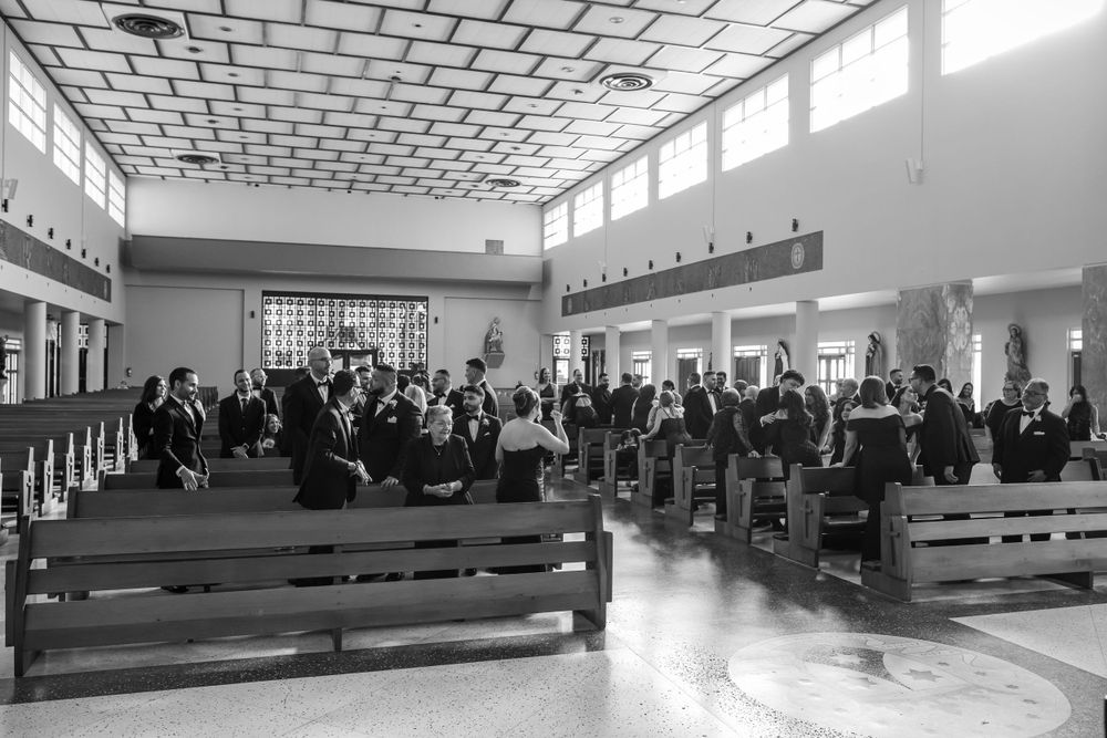 Black and white photo of wedding guests seated in church pews during a ceremony.