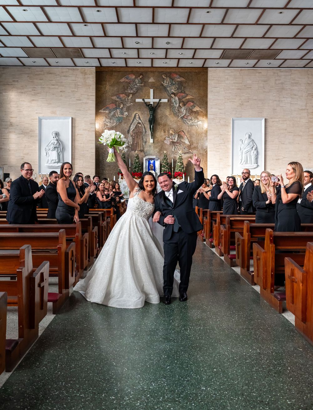 Wedding ceremony in a church with guests celebrating as newlyweds walk down the aisle.