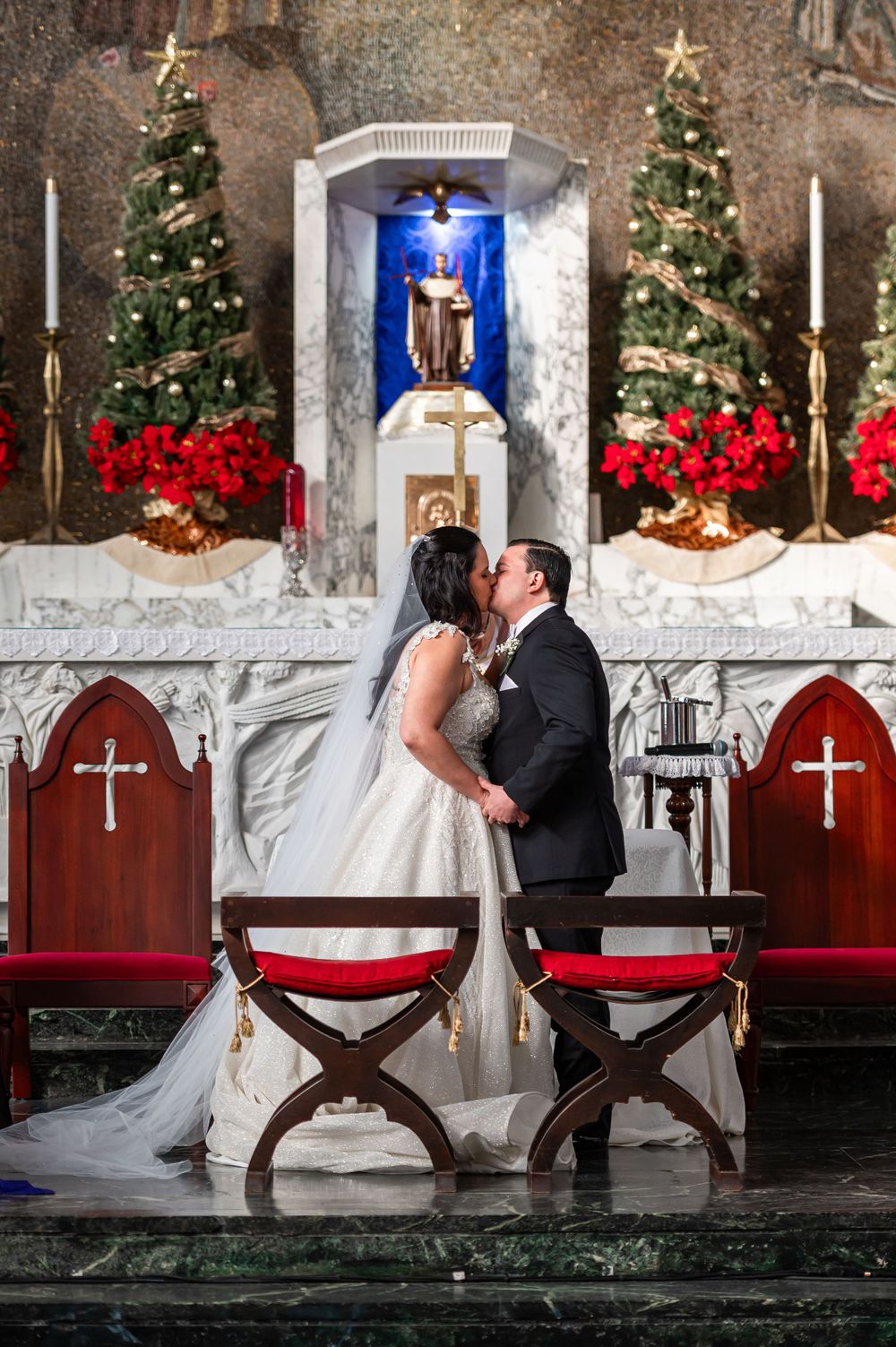 Romantic wedding kiss at decorated church altar with Christmas decorations.