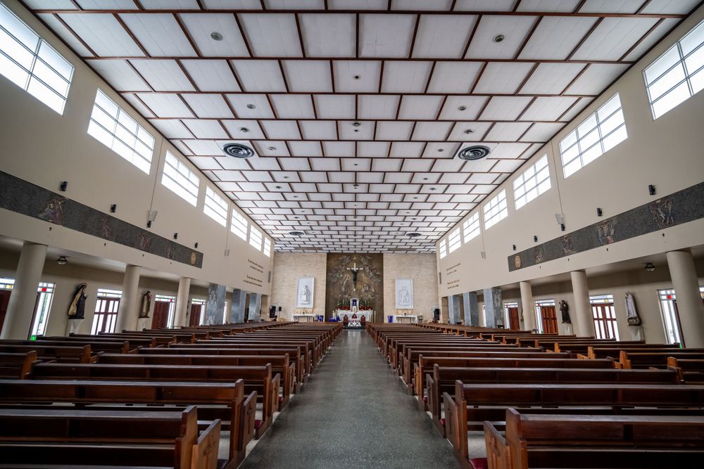 Modern church interior with geometric ceiling design and rows of wooden pews.