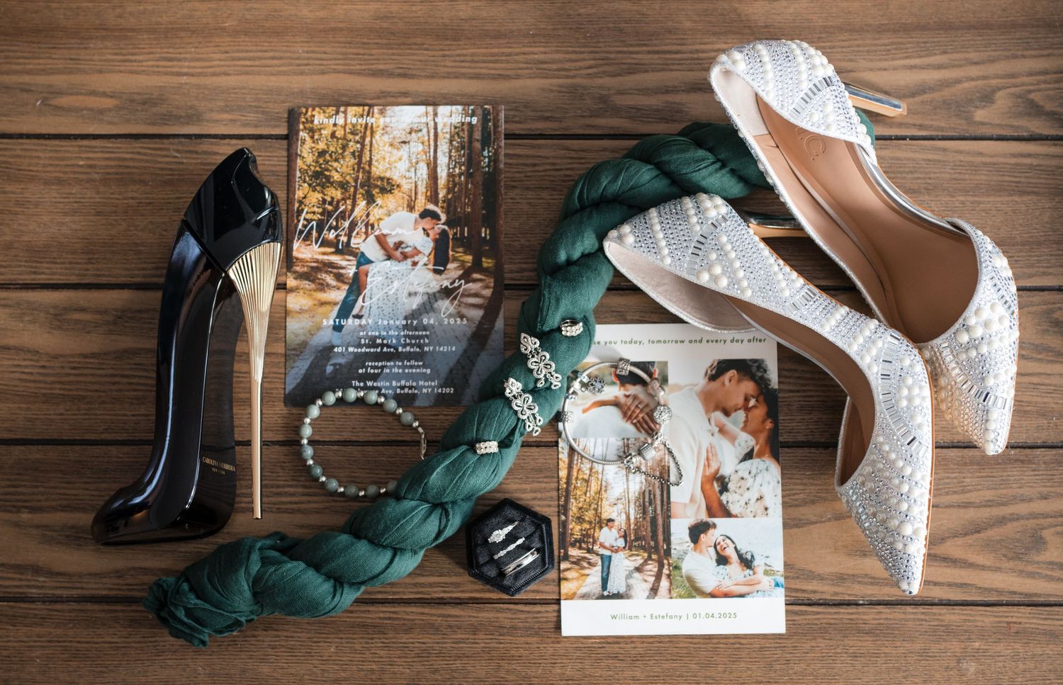 Wedding details flatlay with shoes, photographs, jewelry and green ribbon on wooden surface.