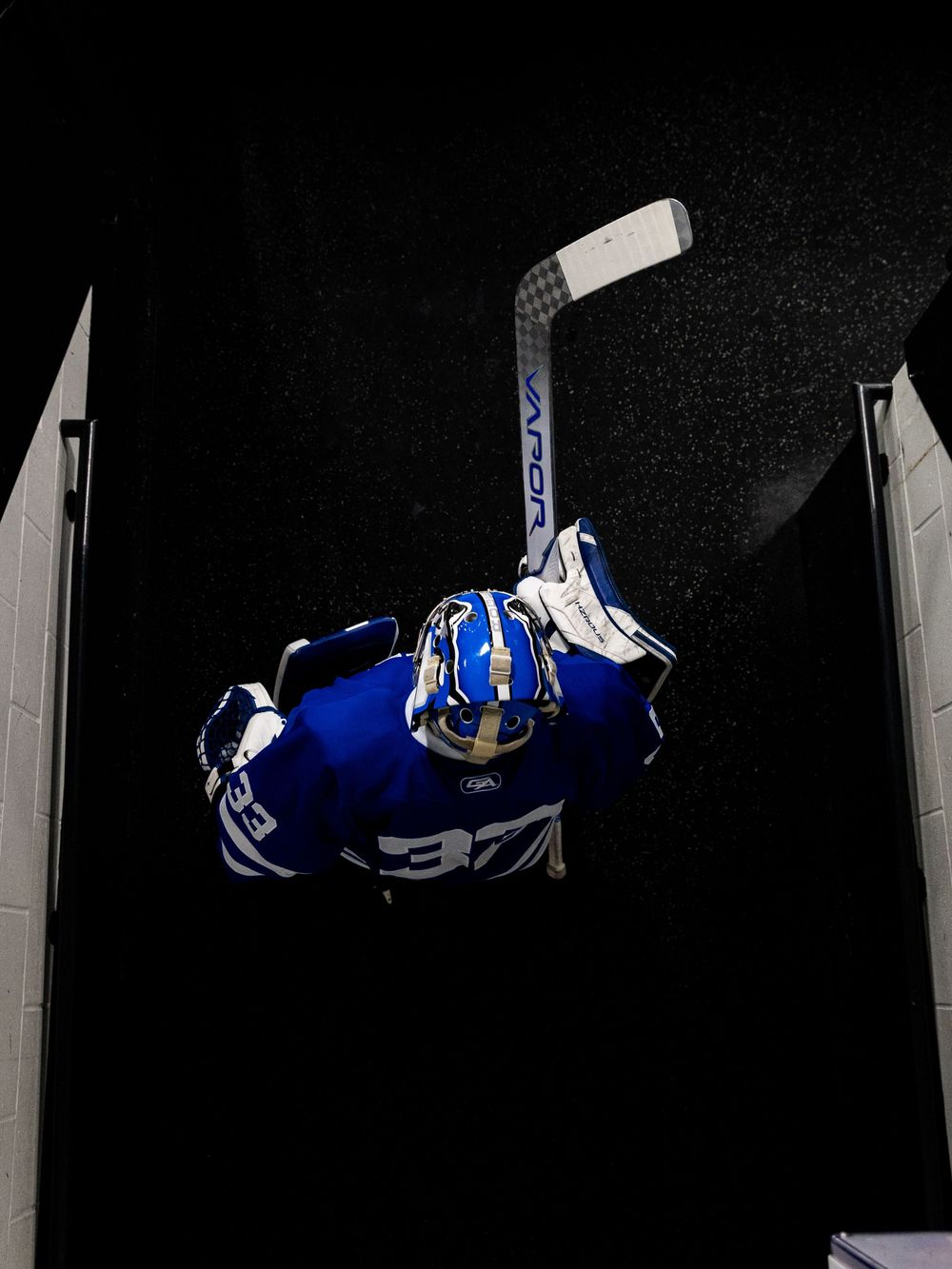 A sequence of images showing a blue and white hockey goalie making a dramatic diving save on a black background.