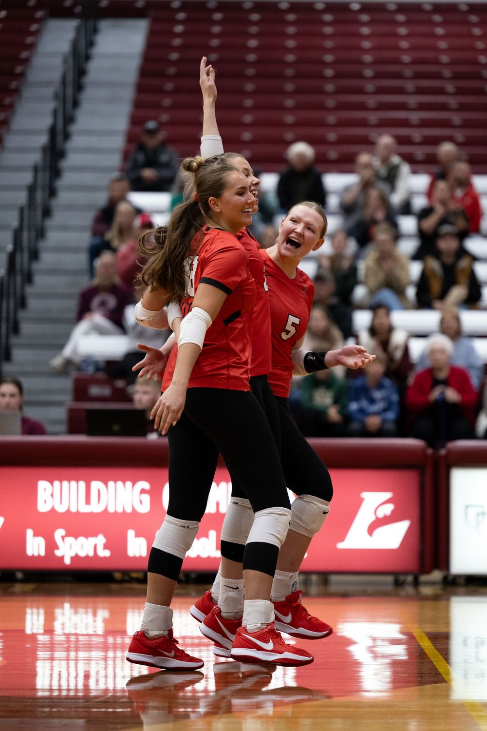 Volleyball players dive and stretch to save the ball during an intense match on the court.