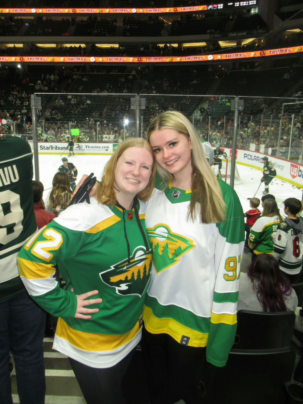 Hockey fans wearing matching green and white jerseys at an arena game.
