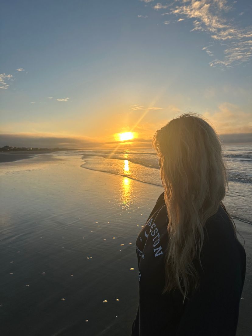Silhouette against vibrant beach sunset with waves reflecting golden light.