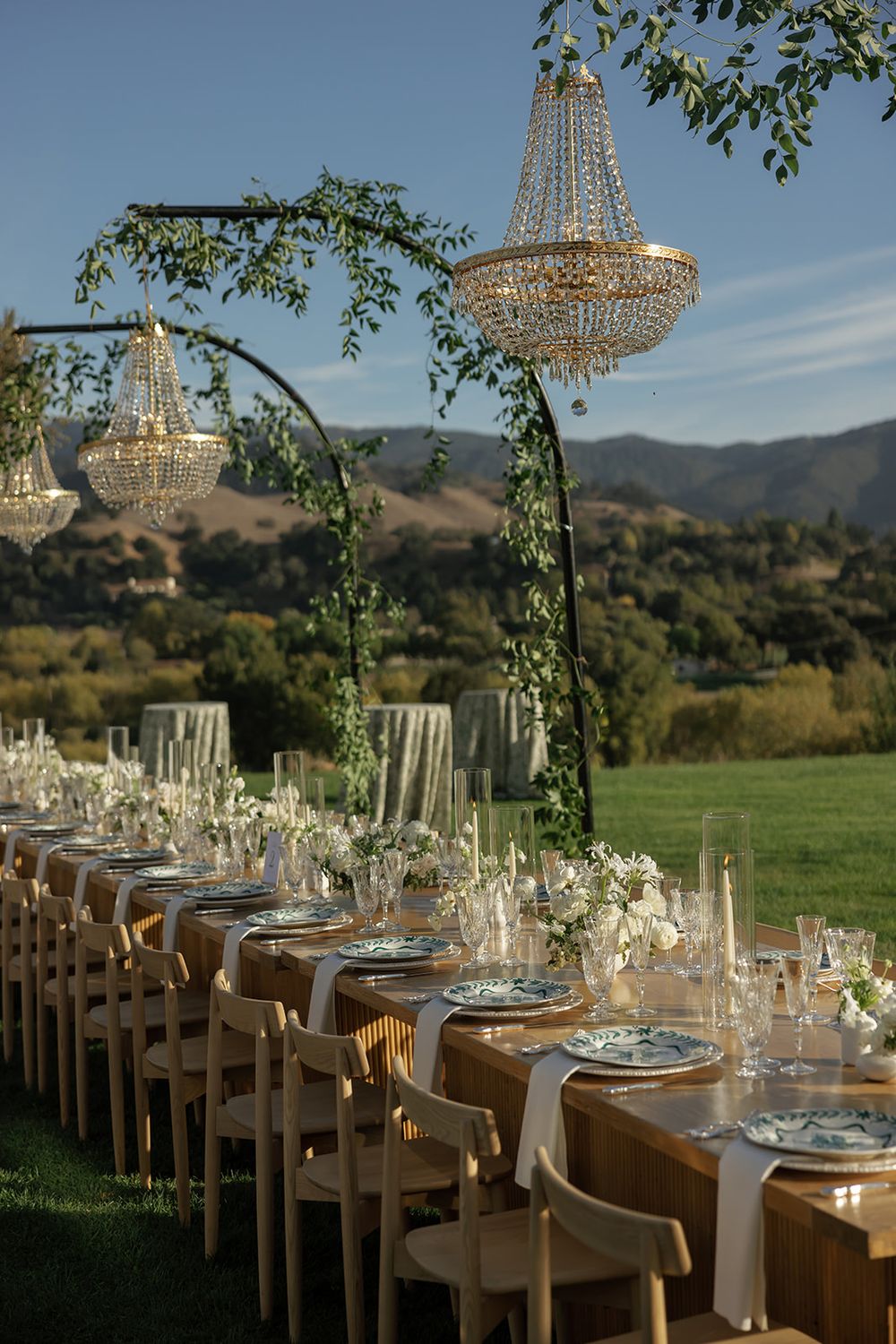 Elegant outdoor wedding reception table setup with crystal chandeliers and mountain views.