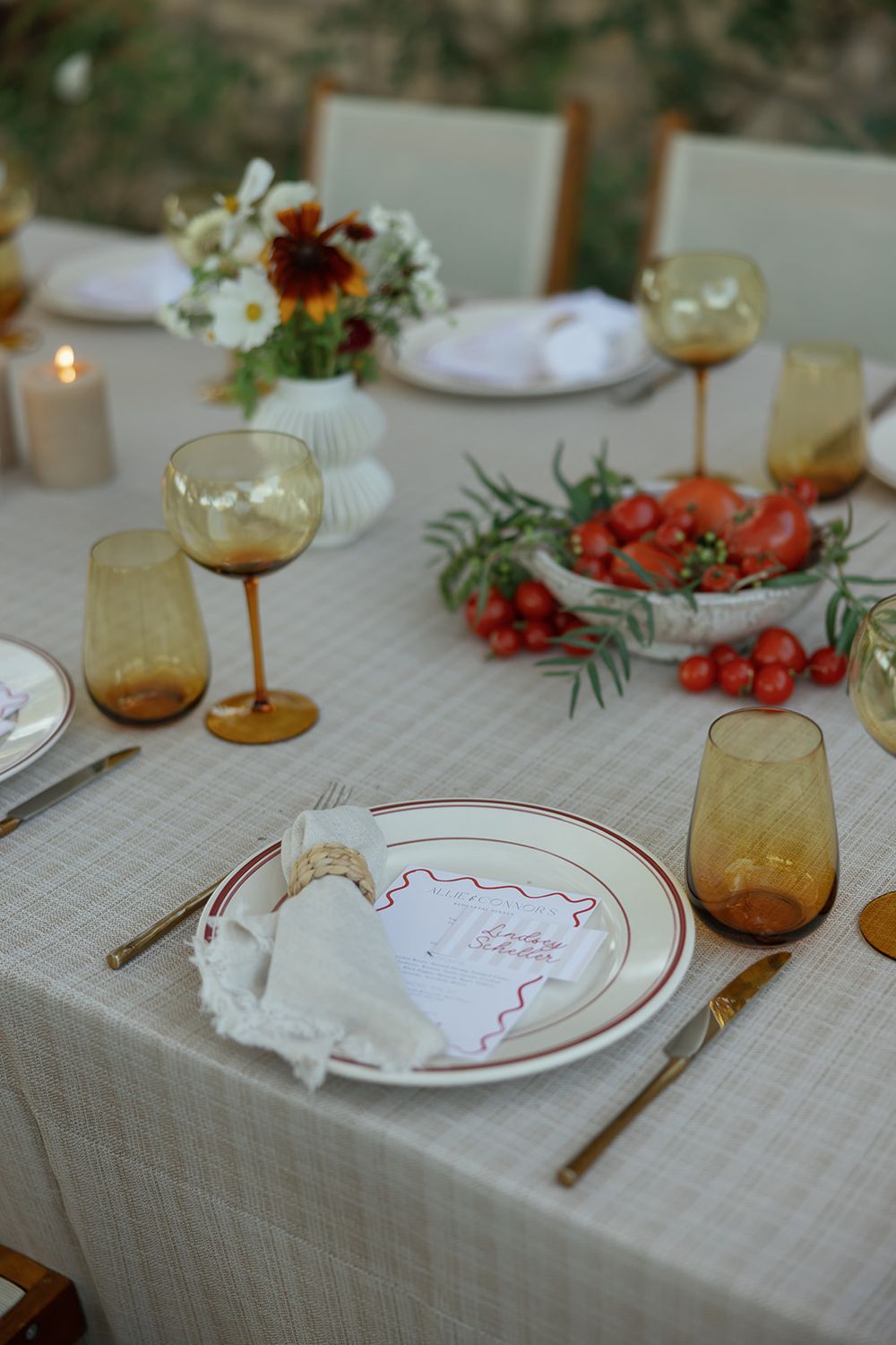 An elegant table setting with amber glassware, white linens, and fresh flowers.