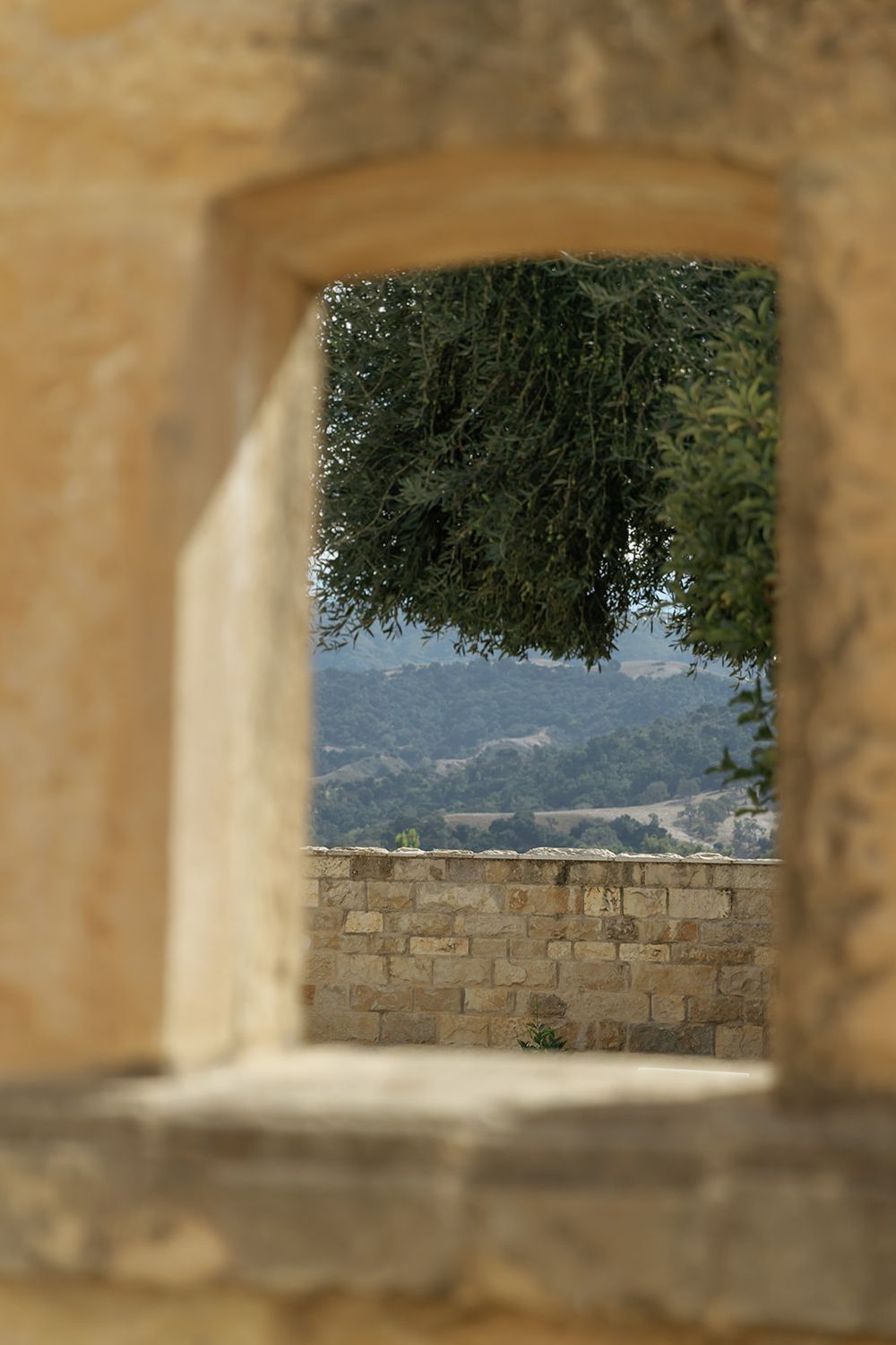 Stone archway frames a scenic mountain view through architectural openings.