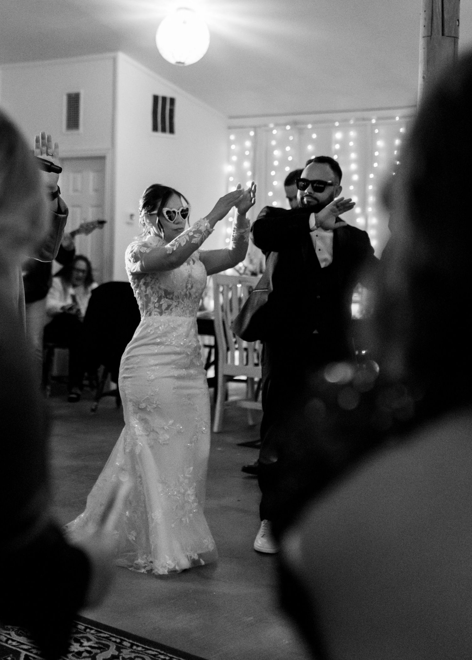 Black-and-white image of the groom gently placing a wedding ring on the bride’s finger.
