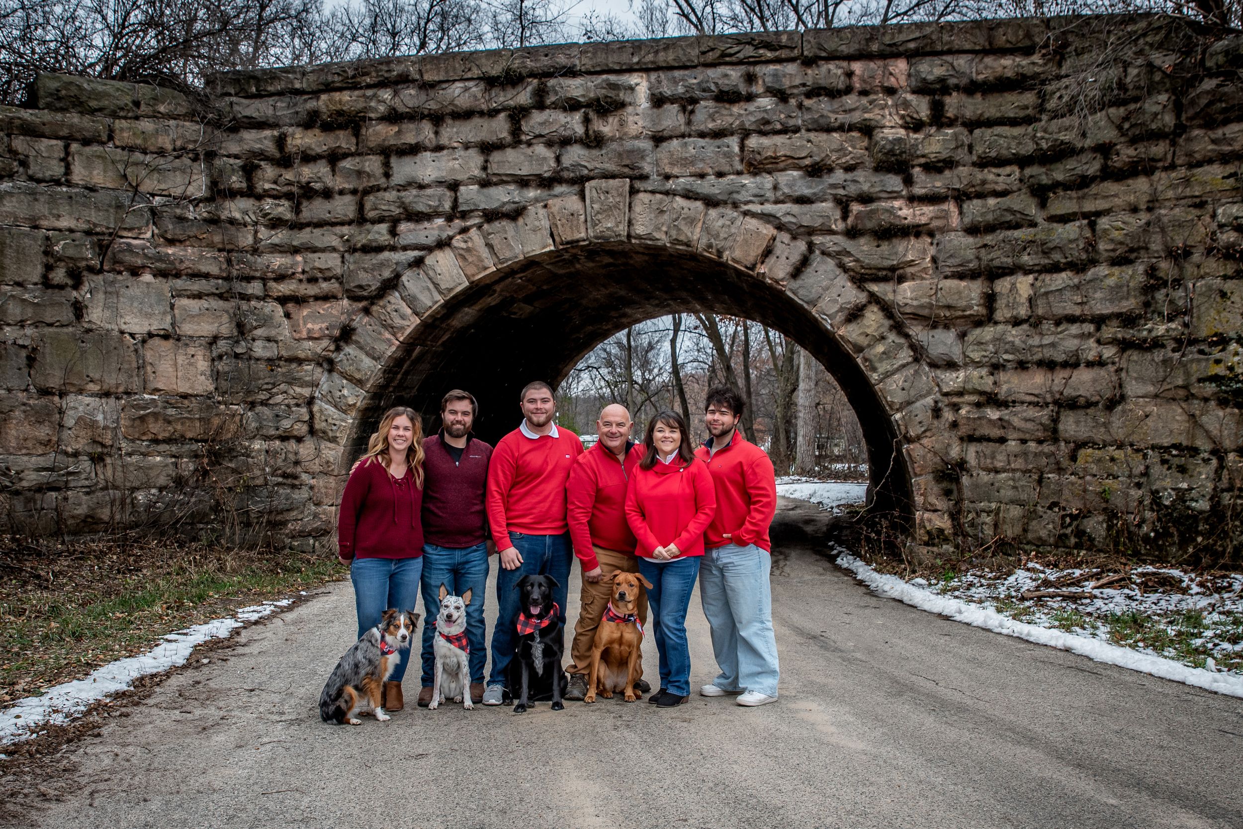 A group poses together in winter against a stone bridge wall featuring classic architectural details in multiple shots.