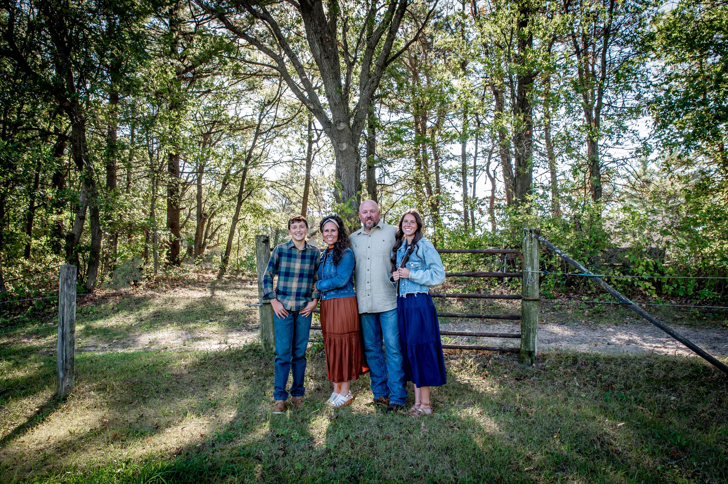 A group of people pose together in a wooded outdoor setting during a photography session.