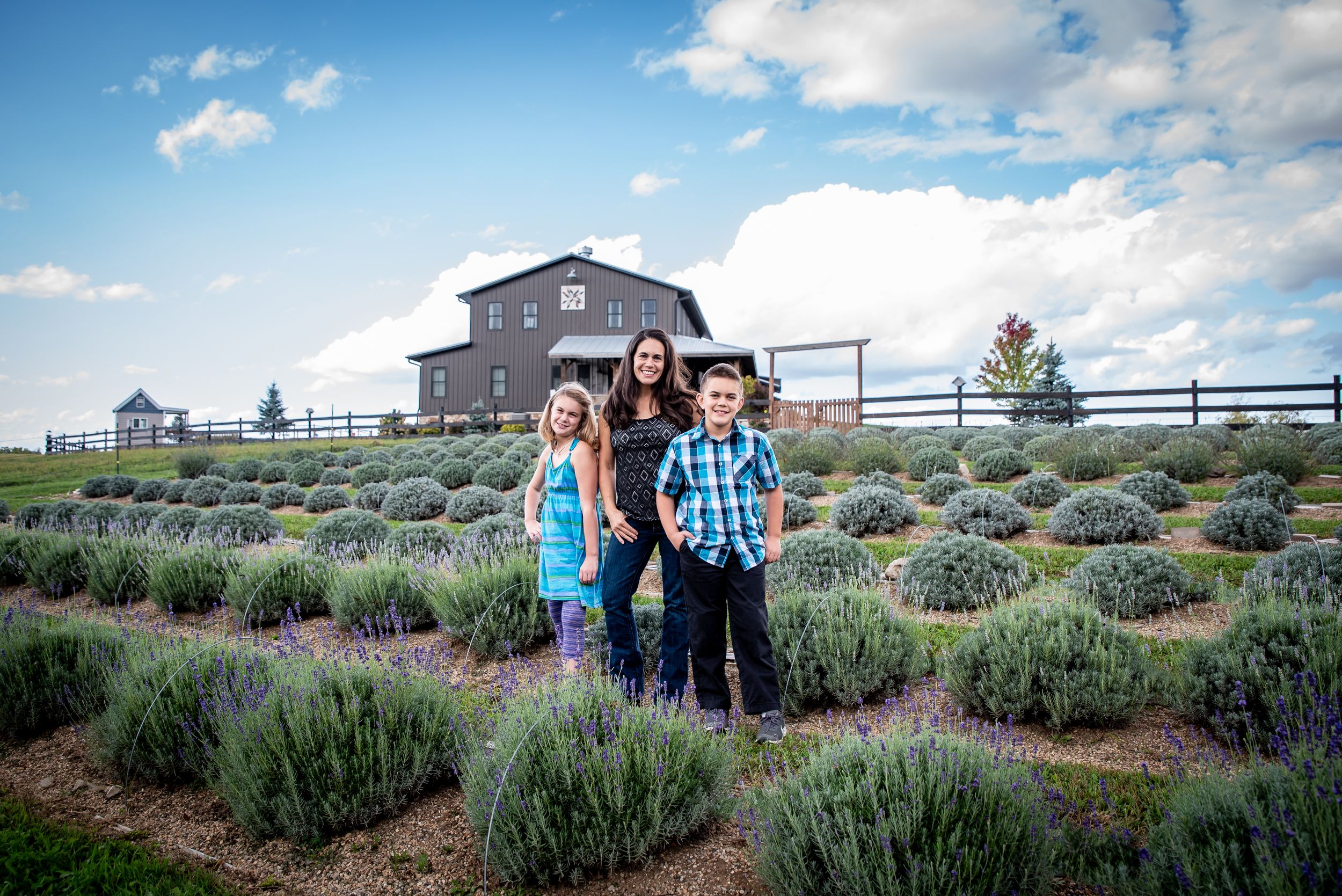 Family portrait session at a scenic lavender farm with rustic fences and golden afternoon light.