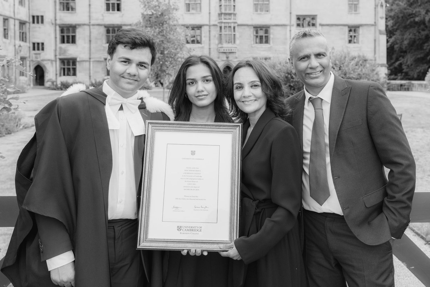 Black and white photo of a group posing together at a formal event while holding a framed certificate.