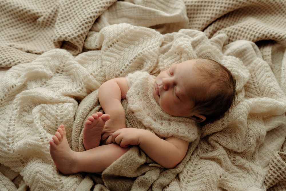 Sleepy newborn in knitted romper