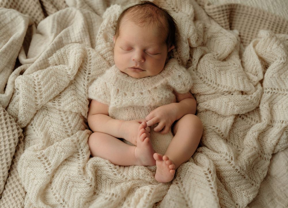 Sleepy newborn in knitted romper