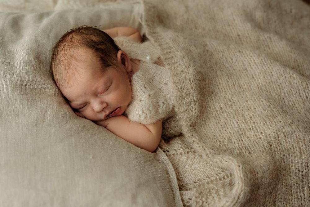 Sleepy new born covered in neutral blanket