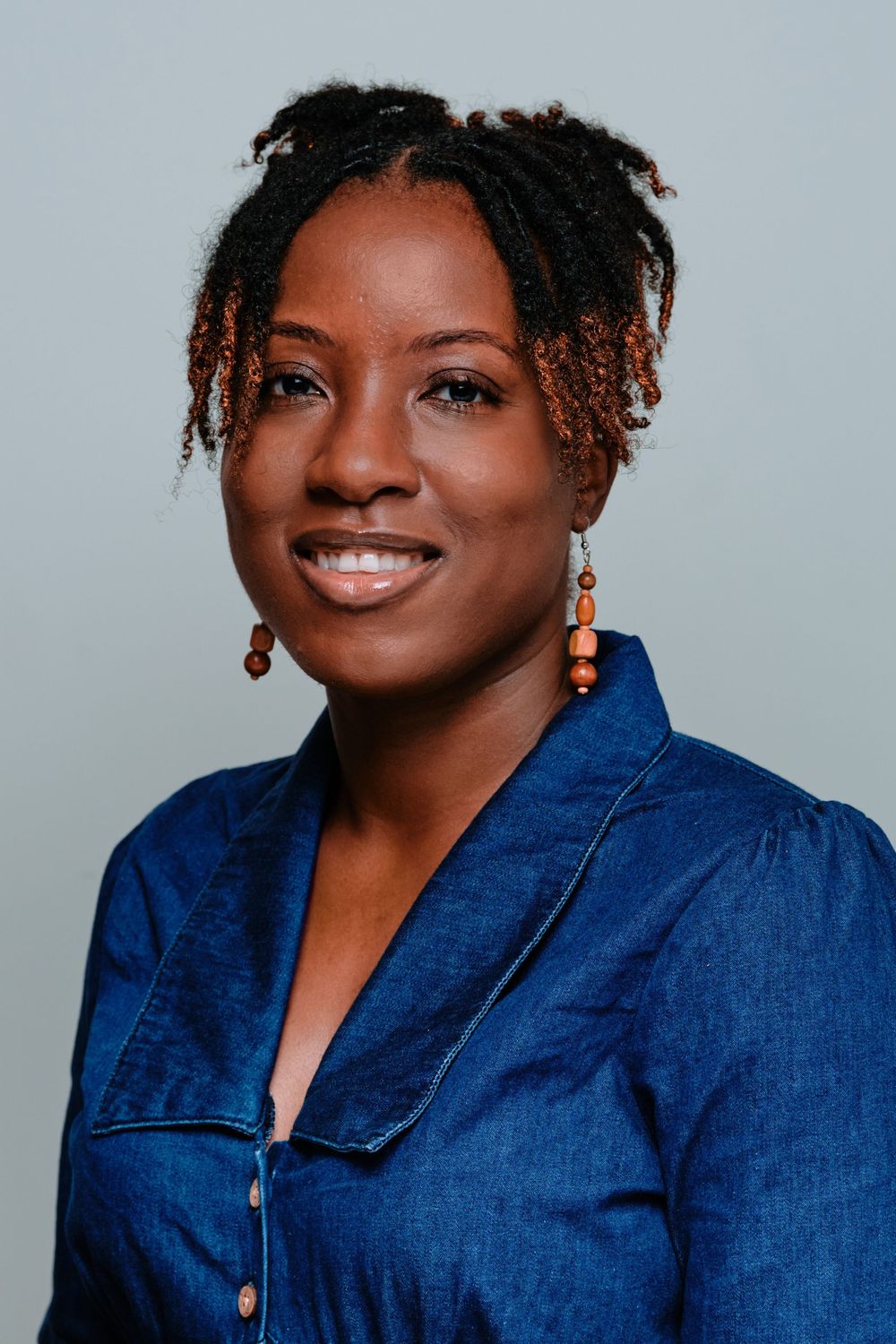 Professional headshot series of a woman in a denim jacket smiling warmly against a light gray background.