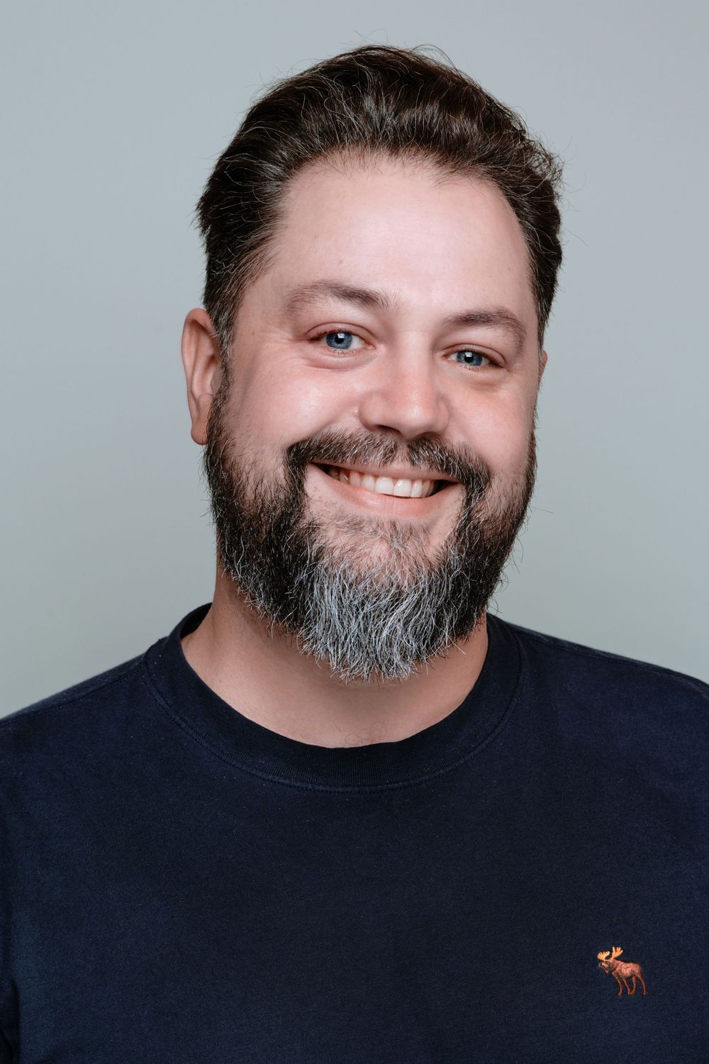 A series of five professional headshots showing someone with a dark beard wearing a navy shirt against a light gray backdrop.