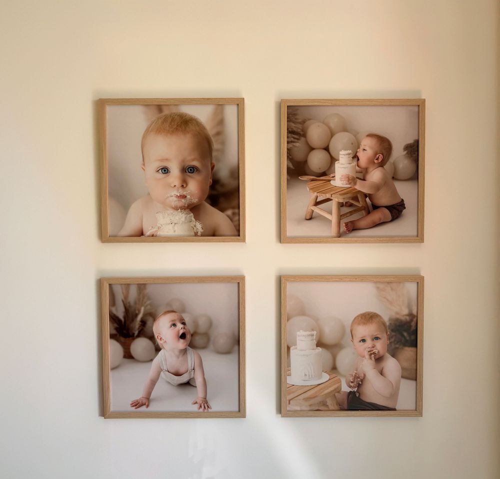 A series of framed baby photographs arranged on a white wall showing various poses and expressions in a minimalist style.
