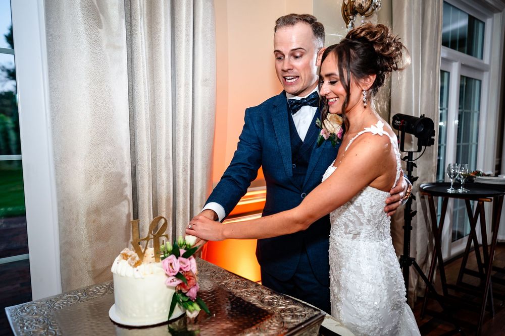 Couple dancing together in an elegant indoor reception venue with romantic lighting.