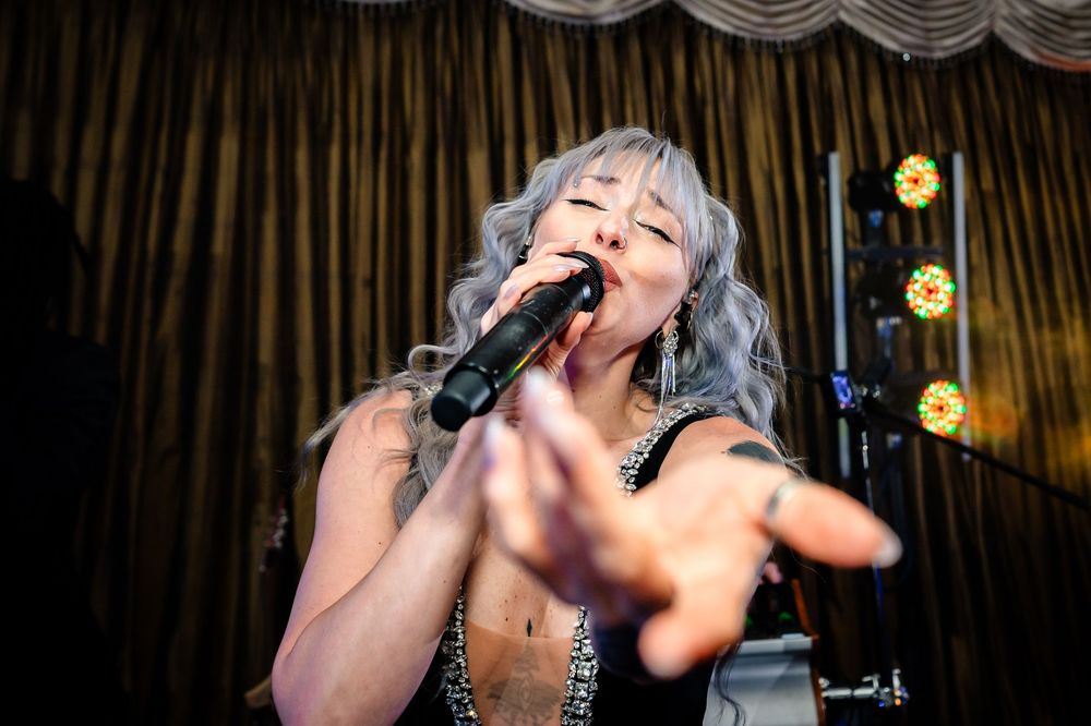 Live band performs energetically on stage at wedding reception.