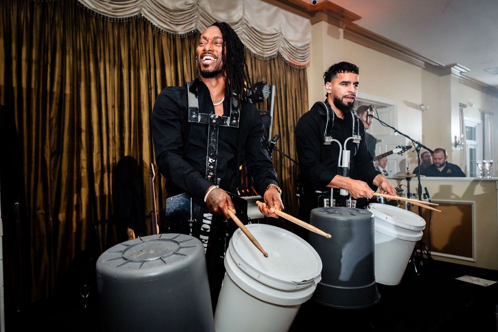 Musicians performing with drums and instruments at an indoor event venue.