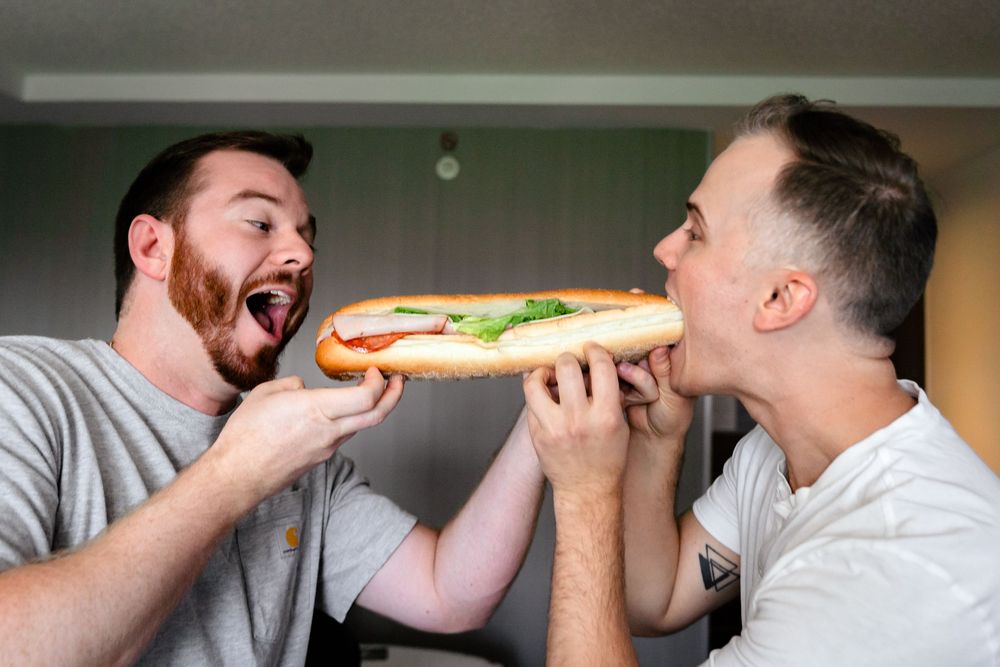 Groomsmen sharing a fun moment eating sandwiches during wedding preparations.