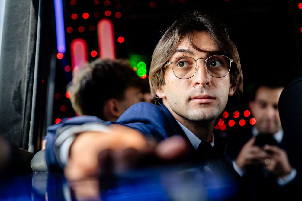 Person in glasses sitting in dimly lit party bus with colorful lighting.