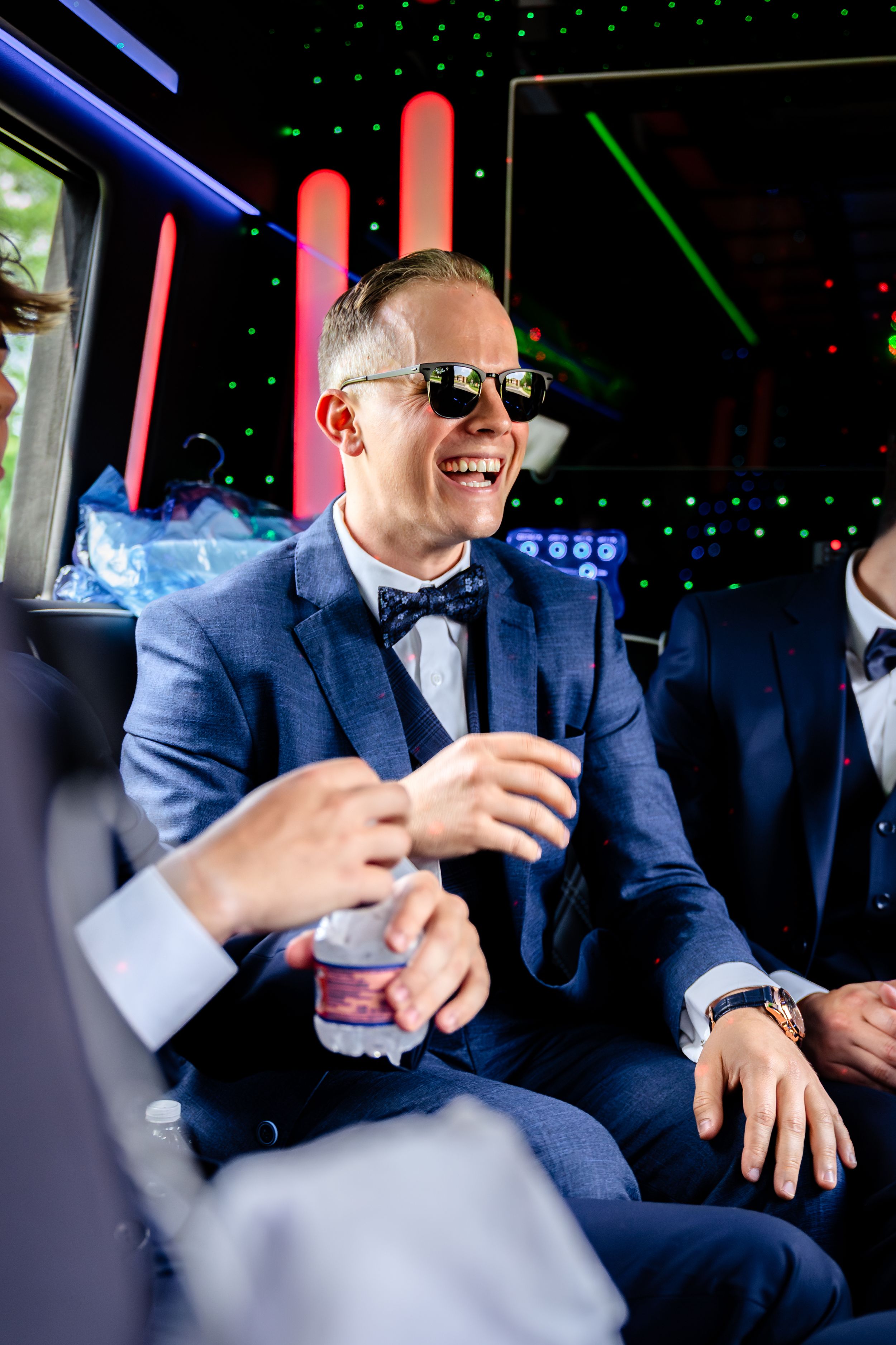 Person in blue suit and sunglasses laughing during celebration in party bus.